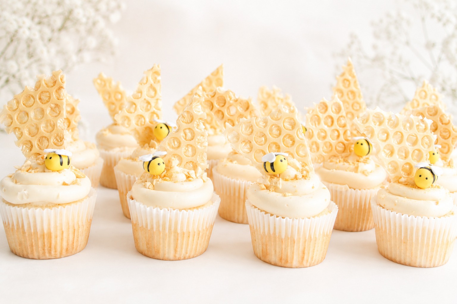 Mom to Bee baby shower cupcakes with honeycomb decorations and tiny yellow-and-black bees